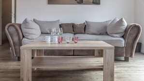 A wooden coffee table with a sofa and cushions in the background.