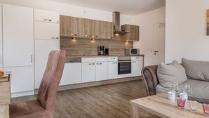 A modern kitchen with white cabinets, a wooden backsplash, and stainless steel appliances.