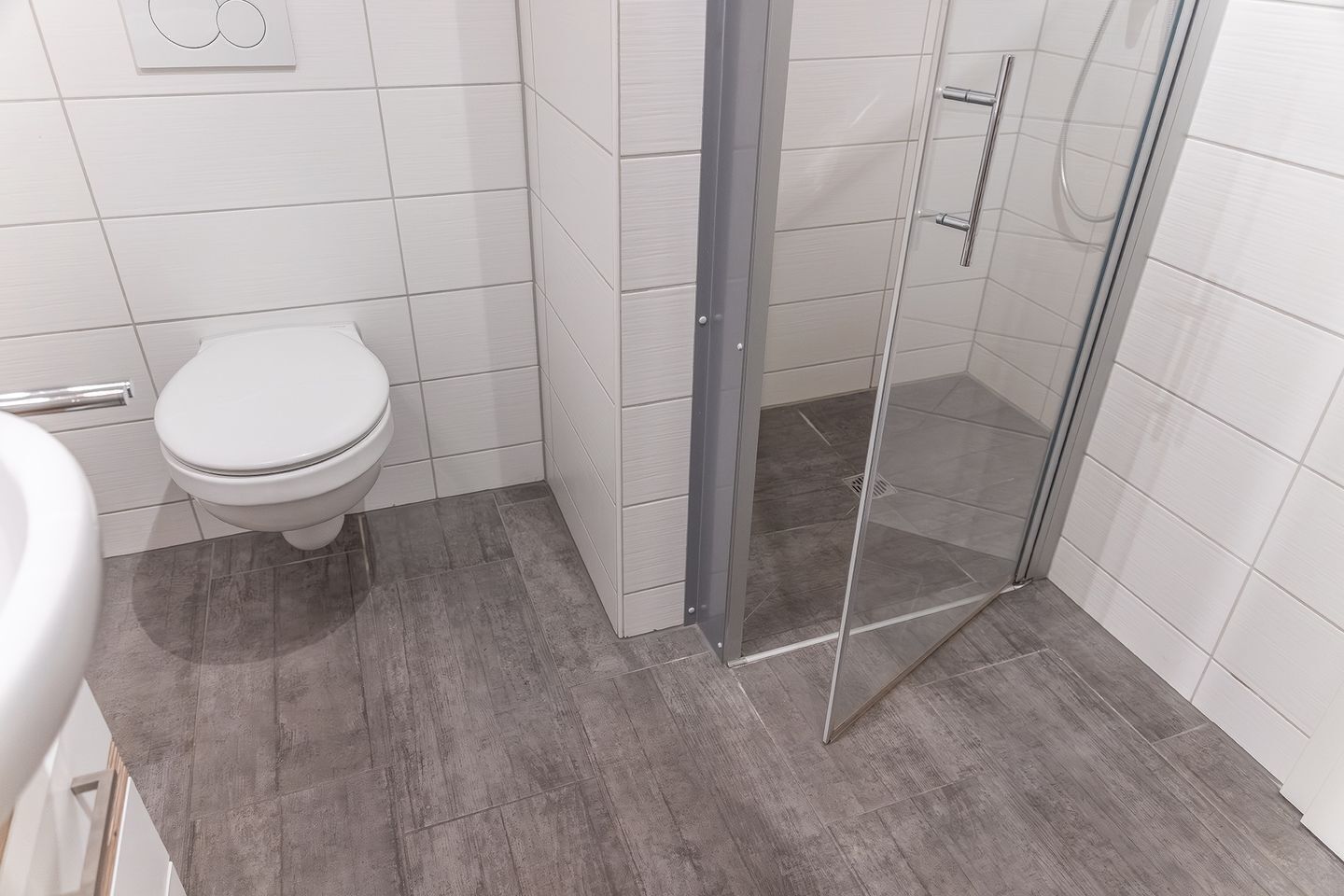 A bathroom with a toilet, a shower with a glass door, and a tiled floor.