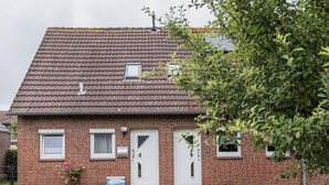 Ein zweistöckiges Backsteinhäuschen mit Ziegeldach, einer Haustür und einem kleinen Fenster.