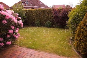 Ein gepflegter Garten mit Rasen, Hecken und blühenden Sträuchern.