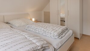 Ein Schlafzimmer mit zwei Betten, einem Kleiderschrank und einem Nachttisch mit Lampe.
