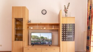 Eine Holz-Multifunktionswand mit Fernseher, Regalen und einer Uhr.