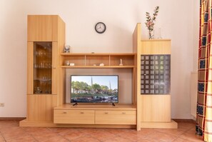 Un meuble de rangement en bois comprenant un téléviseur, des étagÚres et une horloge.