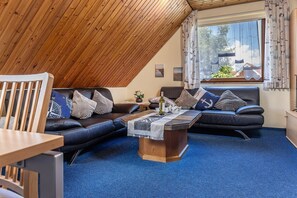 A cozy room with a sloped ceiling, a wooden table, two sofas, and a coffee table.