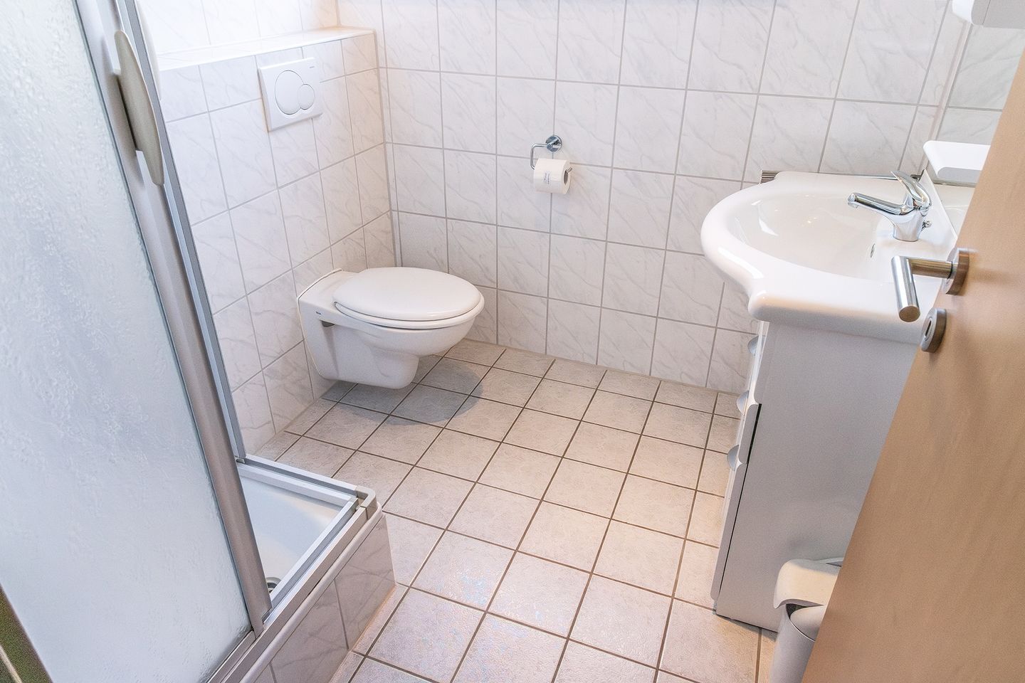 Une petite salle de bain propre, équipée de toilettes, d’un lavabo et d’une douche.