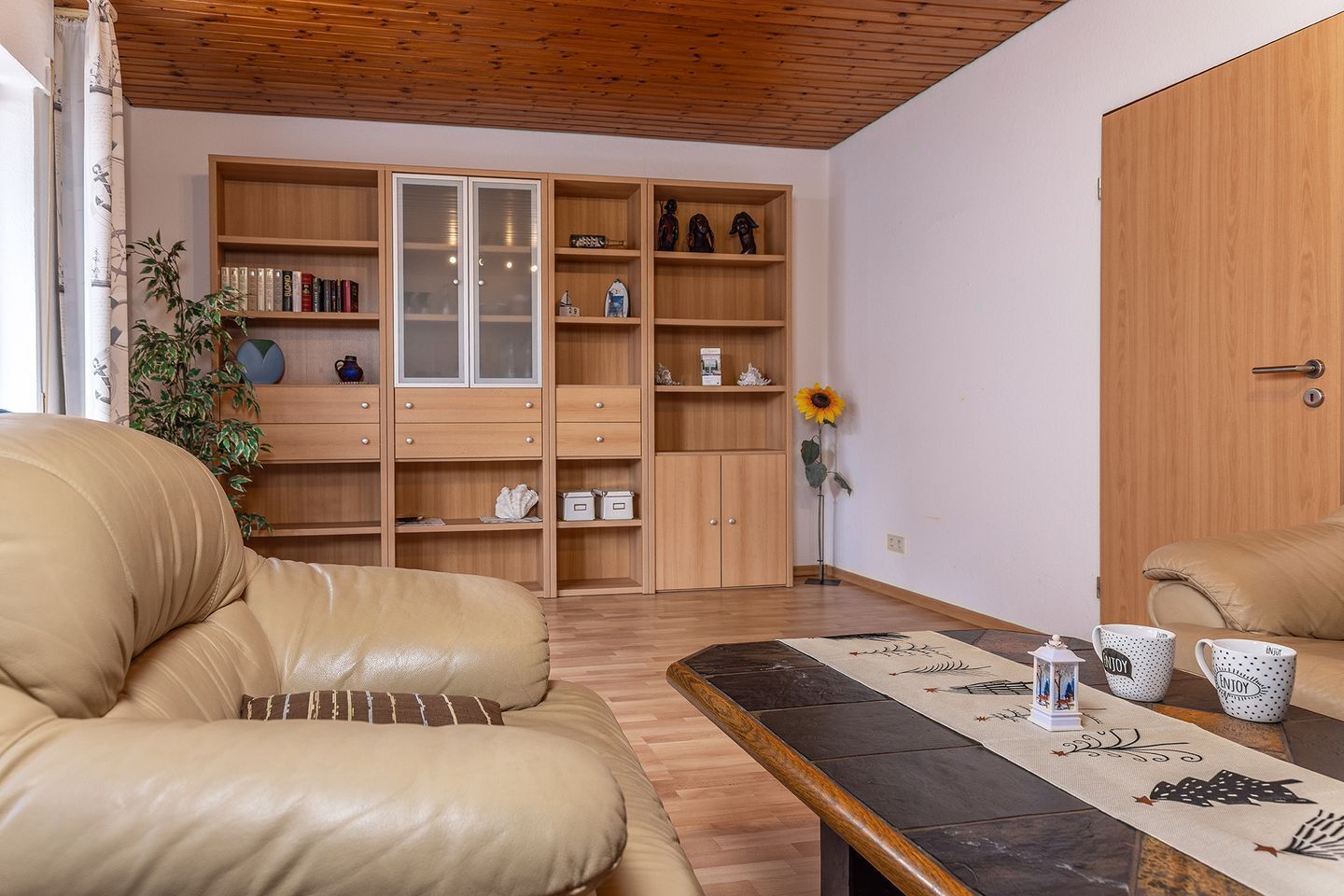 A living room with a sofa, a coffee table, a bookshelf, and a wooden wardrobe.