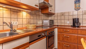 Una cucina compatta con lavello, forno a microonde, fornello e mobili in legno.