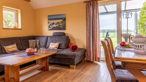 A cozy living room with a sectional sofa, a wooden coffee table, and a dining area with a table set for two.
