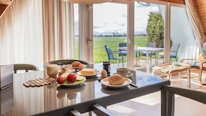 Un comedor con una mesa lista para el desayuno, que incluye huevos, pan y un bol de fruta.