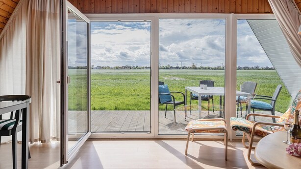Una habitación con un amplio ventanal corredero que da a un espacio exterior con una mesa y sillas.