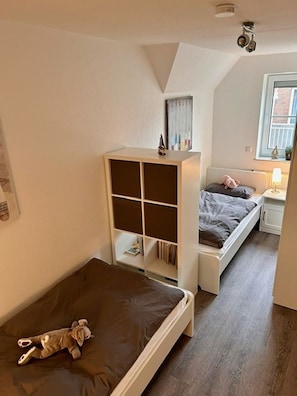 A small, cozy room with a loft bed, a lower bunk bed, and a built-in bookshelf. - 50126 Haus Deichrose - Holiday home "Deichrose" Quiet location, W-LAN, 300 meters to the beach (Wittmund)