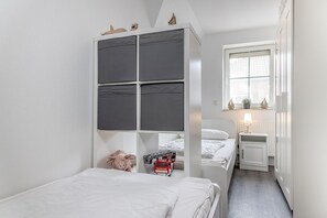 Un dormitorio compacto con literas, una mesita de noche con lámpara, un ventanal con vistas y un radiador.