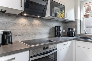 Una cocina moderna con horno empotrado, cafetera y ventana con vistas al exterior.