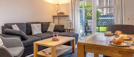 Una sala moderna con sofá, mesa de centro y mesa de comedor dispuesta para el desayuno.