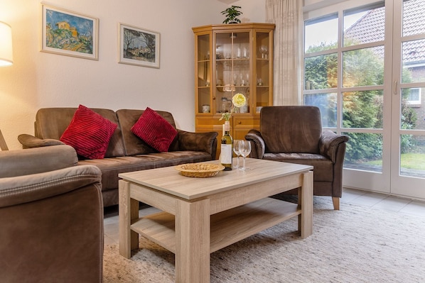 A cozy living room with a brown leather sofa, a wooden coffee table, and a cabinet with glass doors.