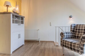 Ett rum med en vit garderob, en rutig soffa, ett element och en lampa med en skeppsdekoration.