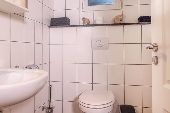 A bathroom with a white sink, toilet, and a towel rack.