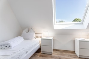 Une chambre à coucher avec un puits de lumière, un lit, deux tables de chevet et une petite table de nuit.