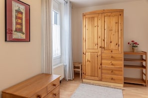 Une pièce comprenant une armoire en bois, une petite table en bois, un radiateur et un tableau encadré accroché au mur.