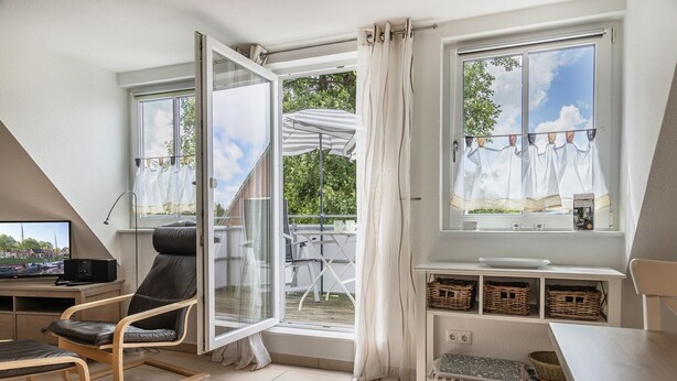 Une chambre moderne dotée d’une grande fenêtre, d’un bureau avec un ordinateur, d’une chaise et d’une petite table.
