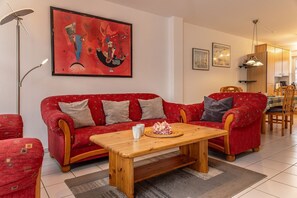 Un salon avec un canapé rouge, une table basse en bois et un tableau accroché au mur.