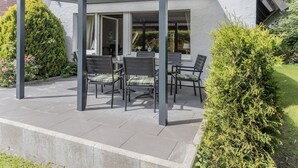 A covered patio area with outdoor seating and a view of a house.