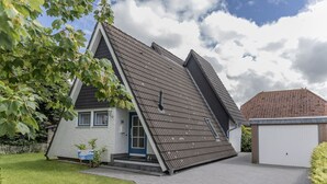 A house with a steeply pitched roof, a front door, and a garage.