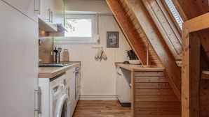 A compact kitchen with wooden accents, a washing machine, and a window.