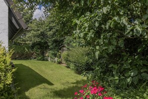 A well-maintained garden with a lawn, flowering plants, and dense foliage. - Vacation home 50013 - Only roof - Holiday home with 3 bedrooms in Carolinensiel (90 (Wittmund)