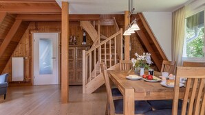 A dining area with a wooden table, chairs, and a staircase leading to an upper level.