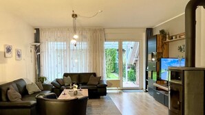 A living room with a sofa, coffee table, and a TV. There is a sliding glass door leading to a balcony.