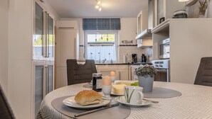 A modern kitchen with a dining table set for two, featuring a sandwich, eggs, and condiments.