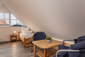 Un acogedor dormitorio tipo loft con una cama de madera, una mesita de noche con una lámpara, una silla y una mesa con una planta en maceta.