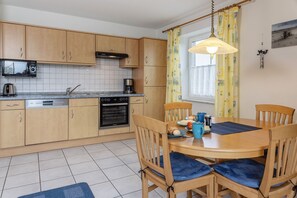 Et moderne køkken med træskabe, indbygget ovn og spiseplads med bord og stole.