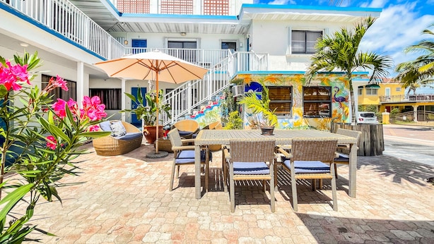 A courtyard with wicker furniture, a covered seating area, and a staircase leading to upper floors. - Ocean's Sound Hotel (Hollywood)