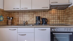 A kitchen with white cabinets, a tiled backsplash, a sink, a coffee maker, and an oven. - Vacation apartment 50036 - Comfortable and cozy: The vacation apartment is located in (Wittmund)