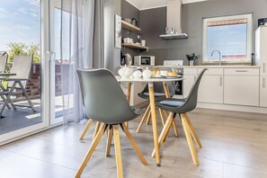 Et moderne køkken med spiseplads, med et bord med stole, en mikrobølgeovn og et vindue med udsigt.