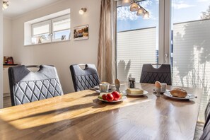 A dining area with a wooden table, two chairs, and a breakfast setting including eggs, toast, and fruit. - 50047 Krabbenhaus House - Modern and comfortable: This stylish corner townhouse measuring approximately (Wittmund)