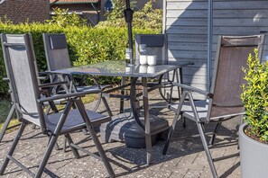 An outdoor patio with a glass table, metal chairs, and a potted plant. - 50047 Krabbenhaus House - Modern and comfortable: This stylish corner townhouse measuring approximately (Wittmund)