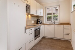 Een moderne keuken met witte kasten, roestvrijstalen apparatuur en een houten aanrecht.