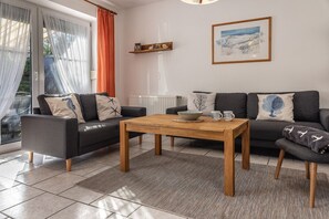 Ein modernes Wohnzimmer mit einer Sofagarnitur, einem Holztisch und einem Essbereich.