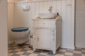 A bathroom with a white sink, a toilet with a blue seat, and a white tiled floor.