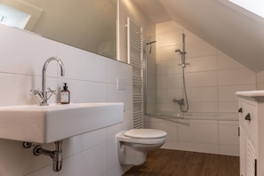 A modern bathroom with a white sink, toilet, and shower. - 50111 Fisherman's Loft - Detached Vacation Home at the Friedrichsschleuse – (Wittmund)