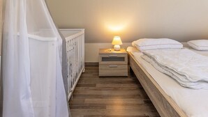 Une chambre à coucher avec un lit, une table de chevet, une lampe et un berceau surmonté d’un dais blanc.