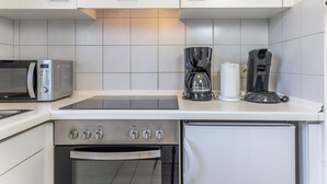 Une cuisine compacte équipée d’un four à micro-ondes, d’une machine à café et d’un four.