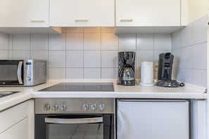 Et lille køkken med mikroovn, kaffemaskine og ovn.
