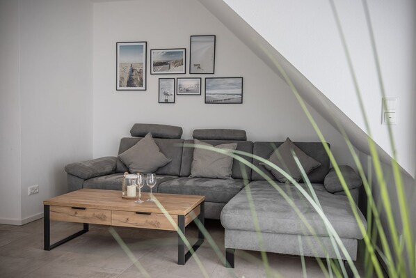 Un salon moderne avec un canapé gris, une table basse en bois et des tableaux encadrés accrochés au mur.