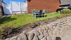 A brick house with a white gate, a lawn, and a stone wall in the foreground. - Diedrich - Holiday apartment Diedrich (Wyk auf Föhr)