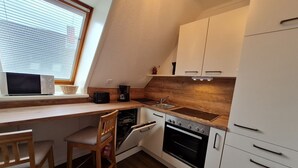 A compact kitchen with a wooden countertop, a built-in oven, and white cabinetry. - Diedrich - Holiday apartment Diedrich (Wyk auf Föhr)